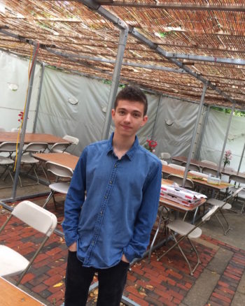 Gabe Hodgkin, a sophomore at Harvard, in the sukkah at Harvard Hillel. Designed by Moshe Safdie, the building's courtyard was designed to accommodate a sukkah. (Penny Schwartz)